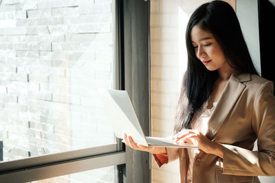 Businesswoman using laptop by window