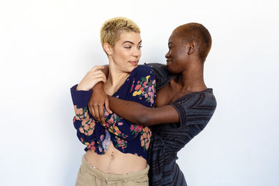 Lesbian couple embracing while standing against white background