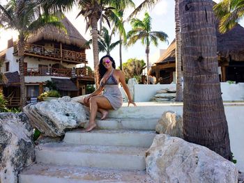 Young woman sitting on palm tree