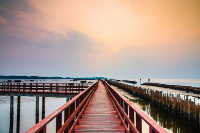 Bridge over sea against sky during sunset