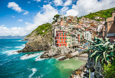 Residential district on mountain by sea against sky