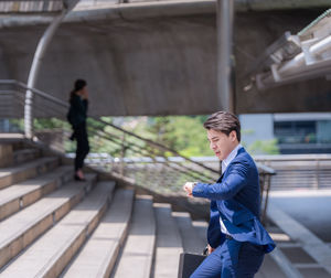 Side view of man and woman standing on footbridge