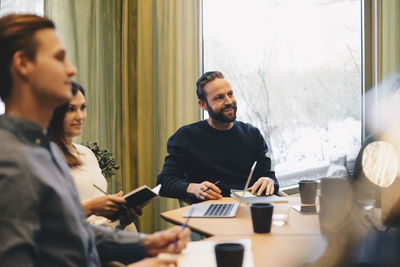 Business people sitting at conference table in brightly lit board room