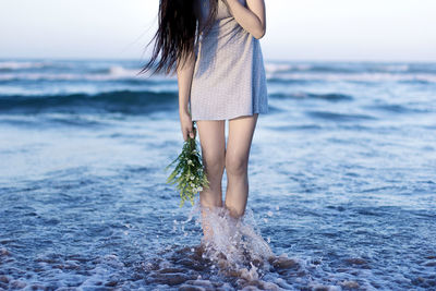 Low section of woman standing at beach against sky