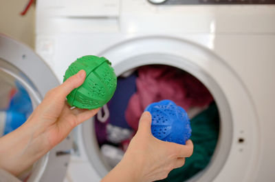 Cropped hands of woman putting detergent in washing machine