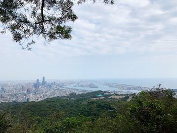 High angle view of city buildings against cloudy sky