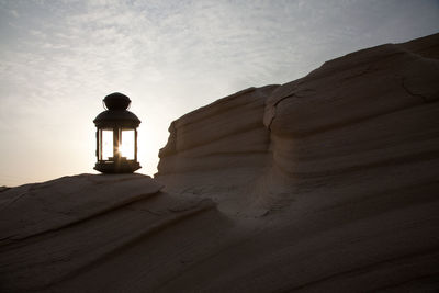 Silhouette man standing on rock formation against sky