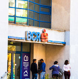 Rear view of people standing against building