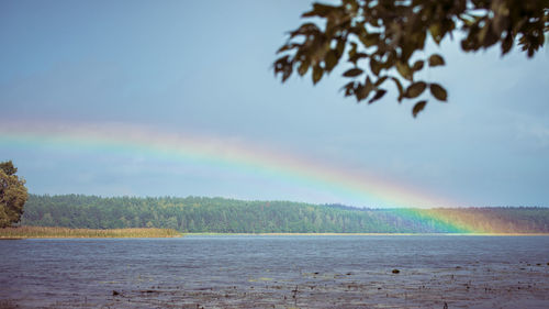 Scenic view of rainbow over lake against sky