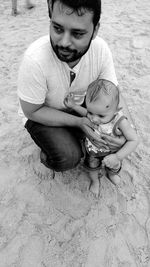High angle view of father with baby boy on sand at beach
