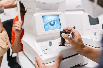 Crop anonymous male doctor ophthalmologist conducting autorefractometry of ocular pressure of female patient on modern equipment of pneumotonometer in ophthalmological clinic