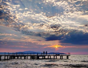 Pier over sea against sky during sunset