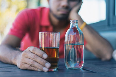 Midsection of man drinking glasses on table