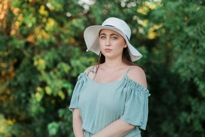 Portrait of beautiful woman wearing hat against trees