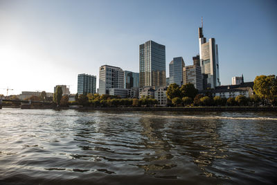 River by modern buildings against sky in city