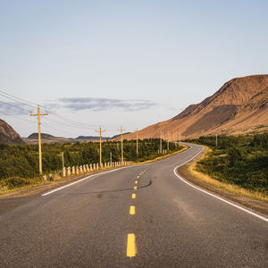 Empty road by mountain against sky