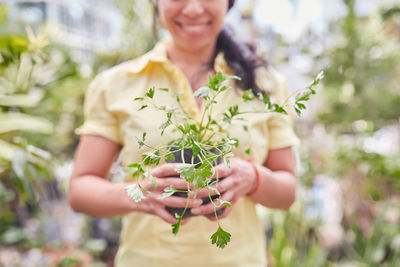 Midsection of woman holding flowering plants