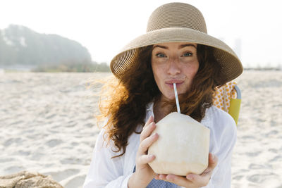 Woman drinking coconut water at beach