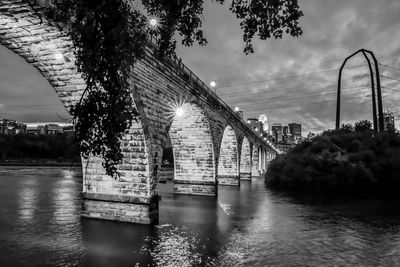 Bridge over river in city against sky