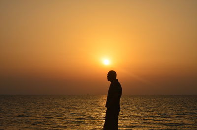 Silhouette man against sea during sunset