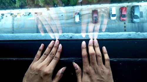 Close-up of cropped hands by window