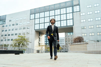 Full length of young man standing against building