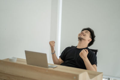 Young man looking away while sitting on table