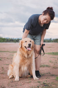 Woman with dog bending on land