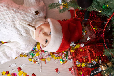 Happy smiling boy lying on floor in christmas santa hat near christmas tree
