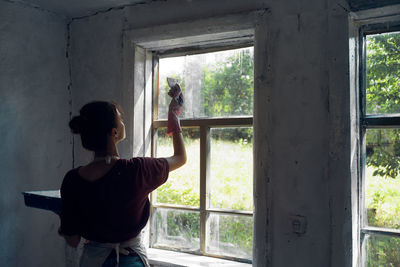 Rear view of young woman painting wall