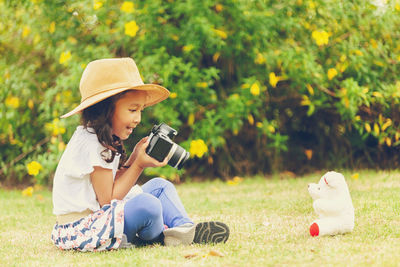 Young woman using mobile phone while sitting on field