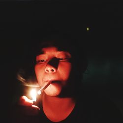 Portrait of man smoking cigarette against black background