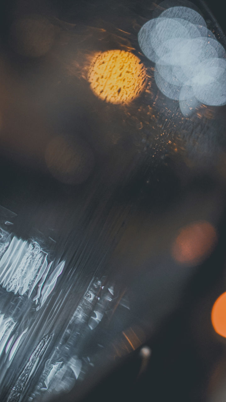 HIGH ANGLE VIEW OF WET GLASS BOTTLE ON ILLUMINATED LIGHT