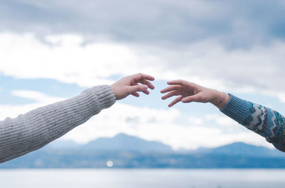 Low angle view of hands holding water against sky