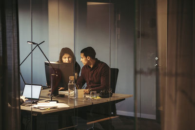 Business people discussing while working at desk in dark office