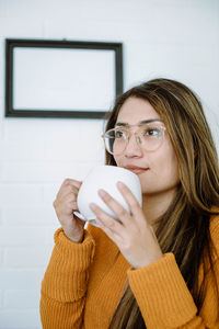 Portrait of young woman drinking coffee at home