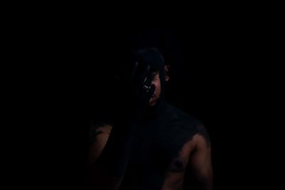 Midsection of shirtless man against black background