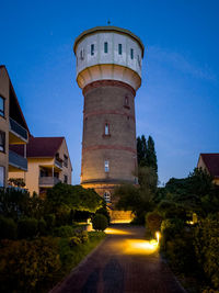 View of lighthouse amidst buildings against clear blue sky