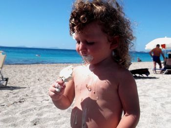 Close-up of shirtless boy on beach against sky