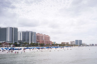 Group of people on beach against buildings in city