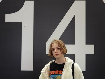 Portrait of girl standing against wall