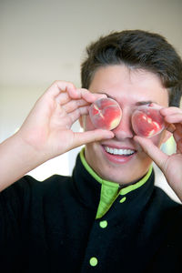 Close-up of boy holding peaches over eyes