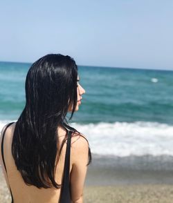 Rear view of woman at beach against clear sky