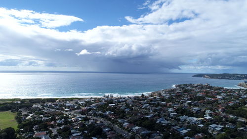 Aerial view of city by sea against sky