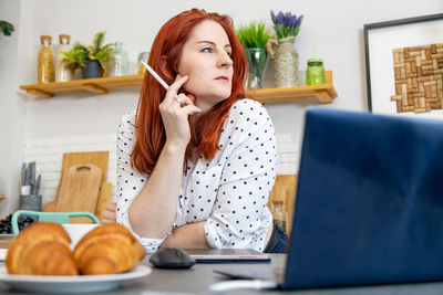 Young woman using phone while sitting on table