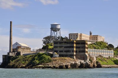 Water tower by sea against buildings against sky