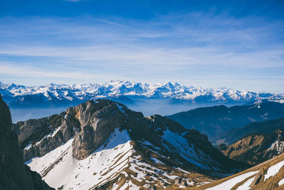 Scenic view of snowcapped mountains against cloudy sky