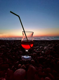 View of wine glass on beach at sunset