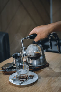 Cropped hand of man pouring coffee in cup