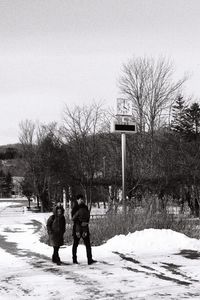 Rear view of people walking on road against sky during winter